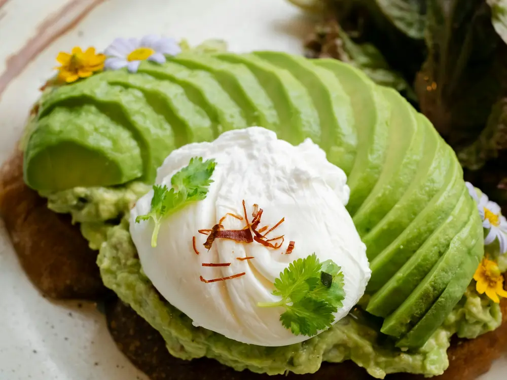 Avocado toast on dark bread topped with a poached egg